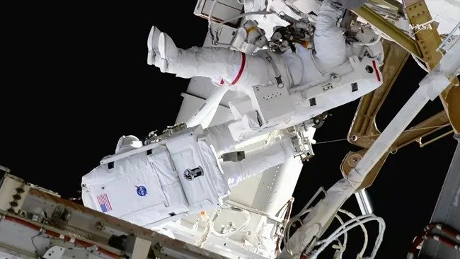 NASA astronauts Jessica Meir (at right) and Anil Menon (facing away from camera) completed a 6.5-hour spacewalk to install solar array mounting hardware outside of the International Space Station on Thursday, Aug. 6, 2026. (Image credit: NASA)