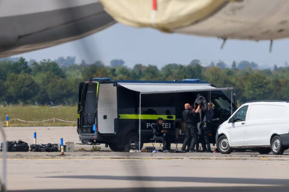 Police officers work in the vicinity of an Antonov cargo plane, near which a drone was found, at Leipzig/Halle Airport in Schkeuditz, Germany, August 5, 2026, after the police said explosives experts examined a drone near a runway, and after a DHL cargo aircraft hit an unknown object as it was.