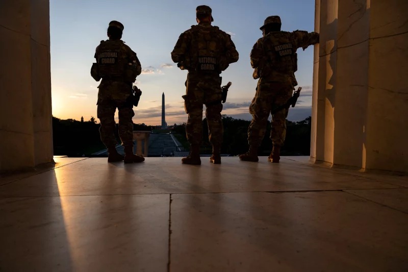 The Washington Monument is seen in the distance as members of the National Guard stand atop the steps at the Lincoln Memorial at sunrise on the National Mall in Washington, DC, on July 23, 2026. Kent Nishimura/AFP via Getty Images
