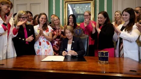 Women smile and applaud as Massachusetts Gov. Maura Healey signs legislation allowing babies to be aborted up to birth. (@MassGovernor/X)