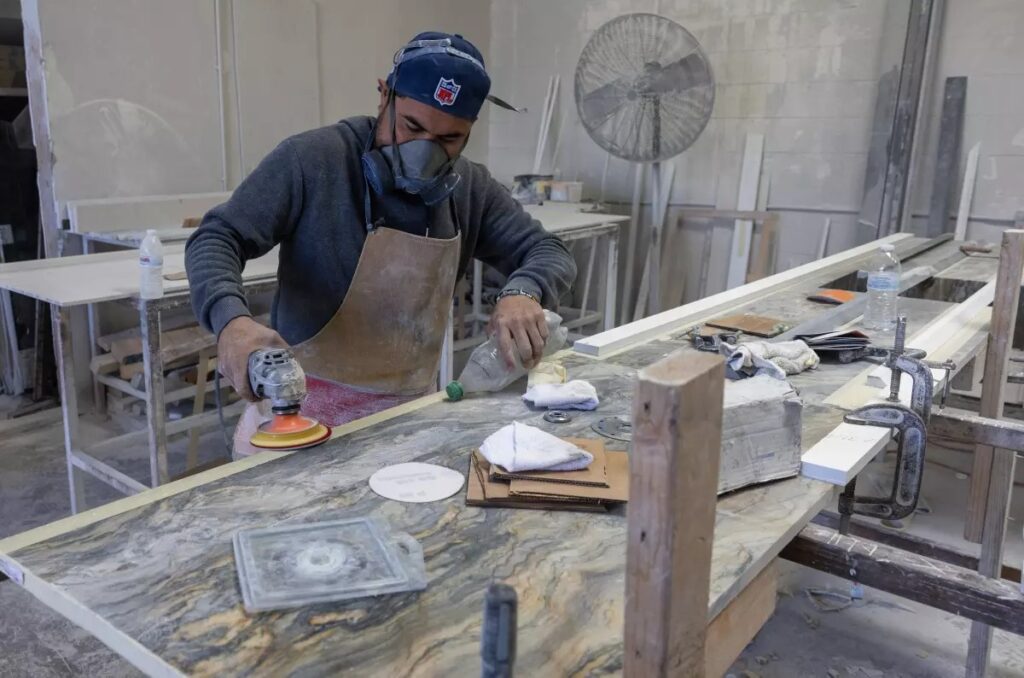 A stone-countertop fabricator at a Sun Valley shop wears a mask to help protect against airborne particles that can contribute to silicosis in October 2023. (Brian van der Brug / Los Angeles Times)