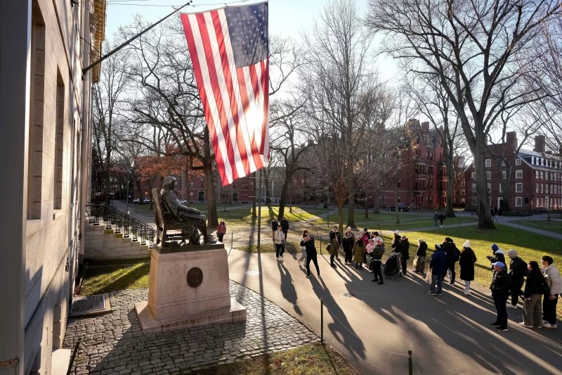 FILE - People take photos near a John Harvard statue, left, on the Harvard University campus, Jan. 2, 2024, in Cambridge, Mass. Steven Senne/AP